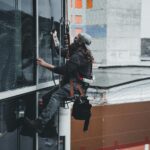 A man cleaning skyscraper windows with a harness, showcasing urban high-rise work.